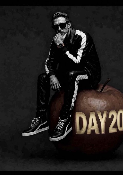 A man wearing sunglasses and a black and white tracksuit sits on an apple-shaped object with the gold text "DAY 20" beside him.