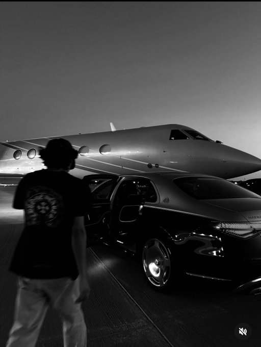 A black and white photo of a person in silhouette walking toward a luxury car parked in front of a private jet on a tarmac.