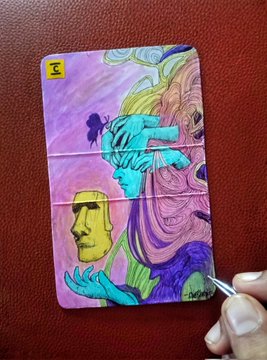 A person's hand is seen painting or peeling back a portion of a colorful artwork featuring a face with flowing hair and hands, resembling a stylized version of the Monna Lisa.