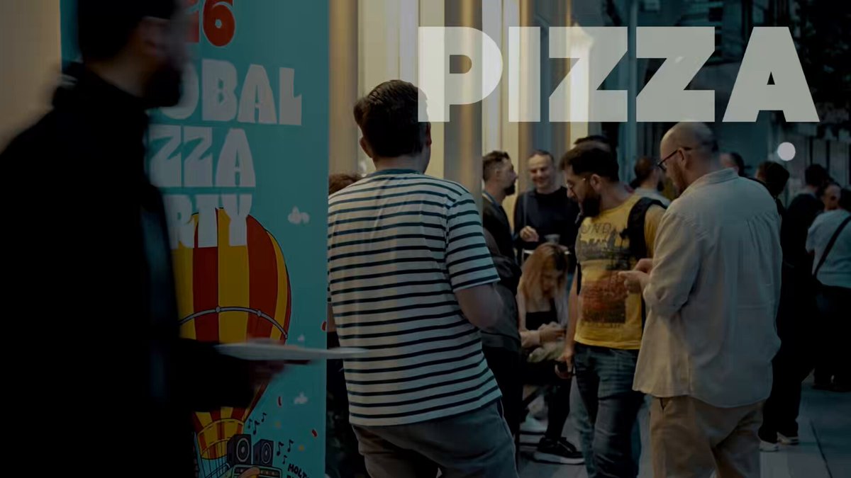 The image features a group of people standing around each other outside a pizza shop or restaurant. The main focus of the scene is a man wearing a striped shirt, who appears to be holding a plate with a slice of pizza on it. There are several other people in the background, some of whom might also be enjoying pizza together. A banner can be seen behind them that says "Pizza", indicating their location or event. The image conveys a sense of community and shared enjoyment as they gather around food to socialize and have fun.