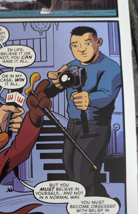 A comic book panel showing a man in a blue shirt holding a camera, with text bubbles reading 'IN LIFE, BELIEVE IT OR NOT, YOU CAN HAVE IT ALL.', 'OR IN MY CASE, WIN IT ALL.', and 'BUT YOU MUST BELIEVE IN YOURSELF... AND NOT IN A NORMAL WAY. YOU MUST BECOME OBSESSED WITH BELIEF IN'.