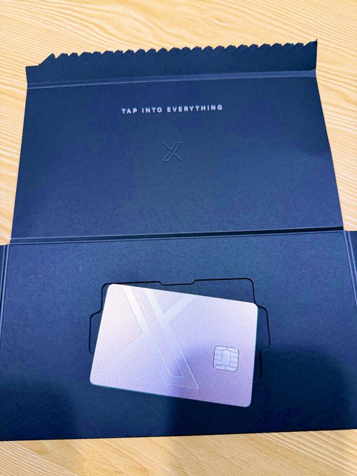 A sleek metallic card with an X logo sits in a dark envelope that reads 'TAP INTO EVERYTHING'.
