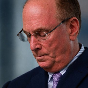 A distinguished man wearing glasses and a purple tie looks down with a somber expression, his serious demeanor fitting the news that BlackRock's ETF has sold $202,500,000 worth of Bitcoin.