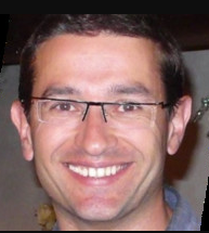 A smiling man with glasses and short brown hair, shown in a close-up portrait against a dark background, likely representing one of the figures mentioned in the post such as Pierre Aubert or Gavin Wood of Parity/Polkadot.