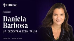 The image features a poster with an image of a woman smiling at the camera, wearing a black blazer over her outfit. The poster includes the title "LF Decentralized Trust" and the text below that says, "LF Decentralized Trust is proud to be a Community Sponsor of …" This indicates that the event is likely related to the concept of decentralized trust, with speakers like Daniela Barbosa being featured at the main stage.
