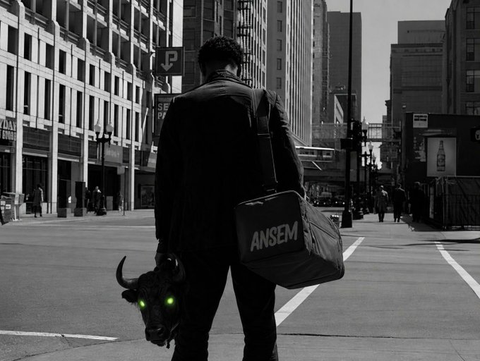 A black-and-white photo of a man in a suit walking down a city street, carrying a duffel bag labeled 'ANSEM' and holding a black bull's head with glowing green eyes.