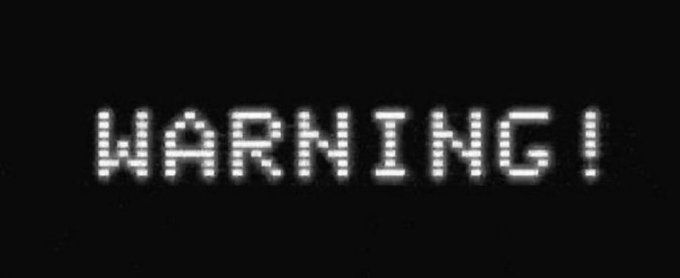 The image displays the word "WARNING!" in pixelated white text on a black background, reinforcing the urgent tone of the accompanying EBS Global Alert post. This visual serves as a direct, impactful representation of the serious message about stocking up on essentials and cryptocurrencies like XRP and XLM.