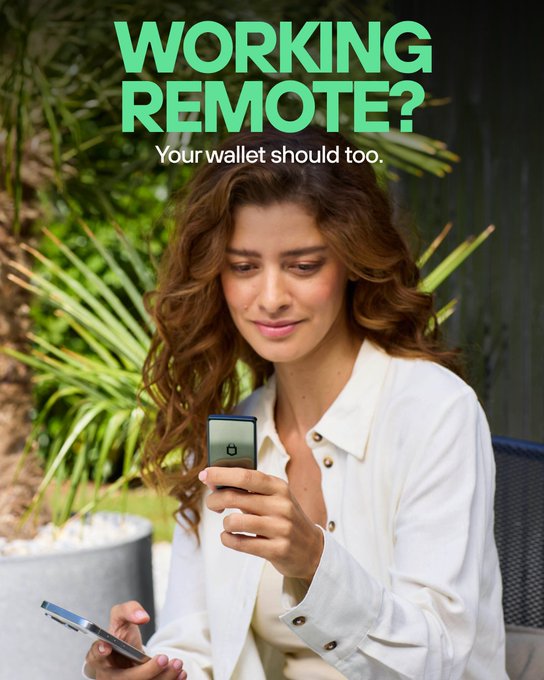 A woman in a white shirt relaxes outdoors, smiling as she checks her smartphone and holds a Trezor Safe 7 hardware wallet, illustrating the freedom of managing crypto remotely via Bluetooth. The bold green text reads "WORKING REMOTE? Your wallet should too," directly reinforcing the post's message about mobile, location-independent crypto security.