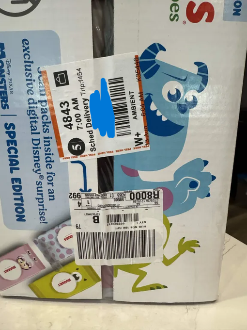 A cardboard shipping box features Monsters, Inc. character graphics and a UPS shipping label indicating scheduled delivery on Tuesday with a delivery zip code of 94554.