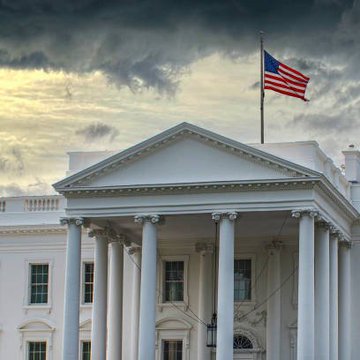 The image shows the White House with its iconic columns and an American flag flying against a dramatic sky, representing the upcoming meeting between crypto and prediction markets executives scheduled for August 19. This visual ties directly to the post's announcement of the high-profile industry gathering at 1600 Pennsylvania Avenue, highlighting the administration's engagement with the crypto sector ahead of the CFTC meeting.