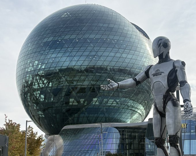 A large humanoid robot statue stands in front of a spherical glass building, with 'EXPONOR' partially visible on the robot's chest.