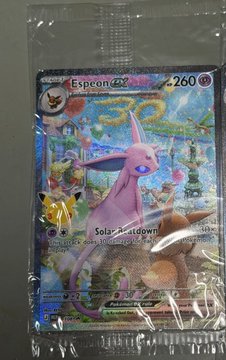 A holographic Pokemon trading card displays Espeon ex (HP 260) with the attack 'Solar Recall' alongside other cards in a protective sleeve.