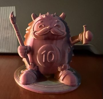 A 3D-printed figurine of a round, pink character with a mustache, holding a trident and a hammer, with the number '10' on its belly.