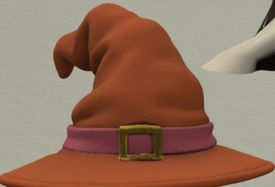 A 3D rendered image of a floppy orange witch's hat with a pink band and gold square buckle, with a black and white witch's nose visible on the right.