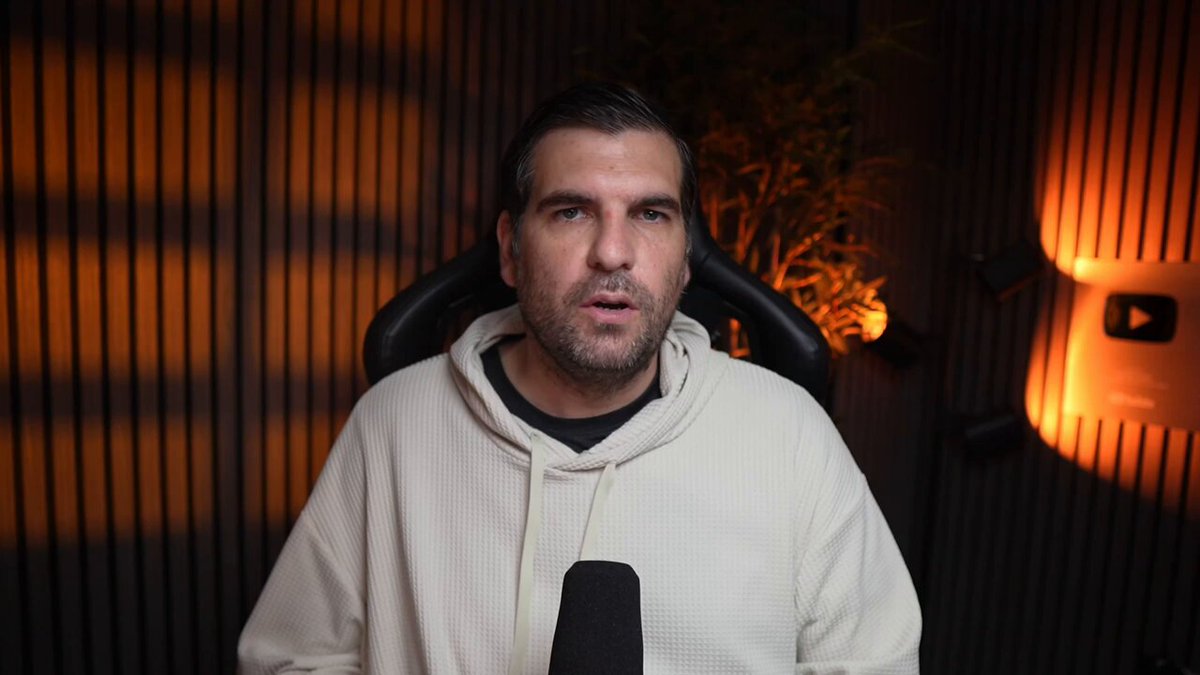 The image shows an adult male wearing a white hoodie with a microphone in front of him, suggesting that he might be hosting or participating in a podcast or online event. The background features a dark wall with orange lights behind him, creating an interesting visual contrast. The caption reads "ICP ALERT: Legacy crypto is LYING about their speed We have been lied to about blockchain speed for years, as marketing campaigns sell theoretical limit metrics achieved only on a controlled test net". This image seems to be related to the topic of cryptocurrency and its impact on the world economy or technology advancements.