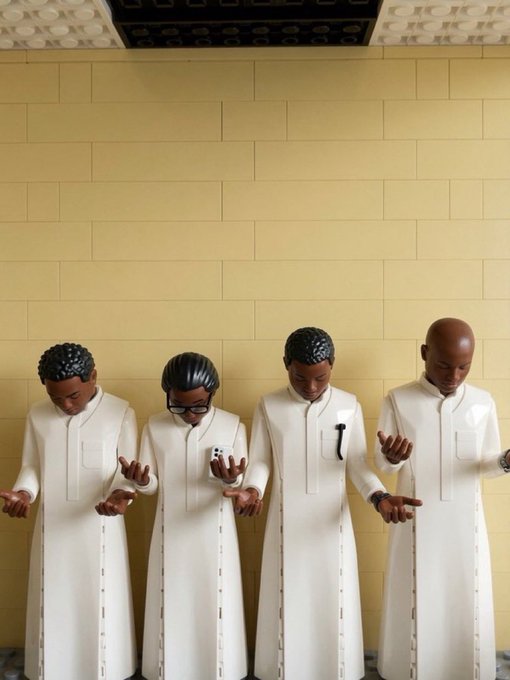 Four small, stylized statues of figures in white robes stand in a row, looking down at their hands; one holds a smartphone and another holds a microphone.