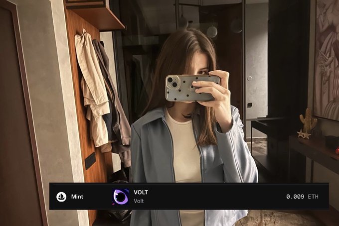 A woman in a light blue jacket takes a mirror selfie holding her phone, with an overlay showing a successful mint on the "Volt" platform for 0.009 ETH. The caption celebrates the mint while thanking PoweredByVolt and LegacyWeb3io for a spot that brightened her last day before starting a new job.