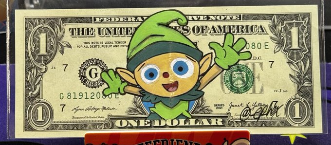 A cartoon elf character wearing a green hat waves cheerfully from atop a framed United States one-dollar bill, which displays "THE UNITED STATES OF AMERICA," "ONE DOLLAR," and serial number "G 81912020 J 7." The image playfully visualizes the caption's "started from a $1" message, symbolizing humble beginnings tied to the VeeFriends brand.
