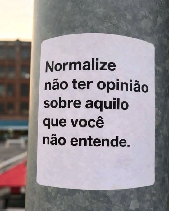 A white sticker on a metal pole with Portuguese text reading 'Normalize não ter opinião sobre aquilo que você não entende.'