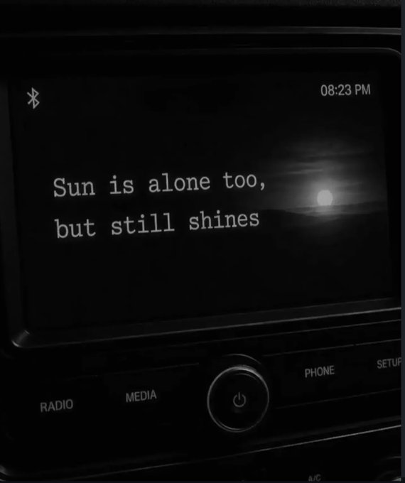 A car's infotainment screen at 08:23 PM displays the quote "Sun is alone too, but still shines" against a nighttime backdrop with a visible moon, paired with a post captioned "Best quote."

The image connects to the post by presenting this motivational quote in an evocative setting—darkness surrounding a lone shining celestial body, reinforcing the message of solitary strength the poster finds inspiring.