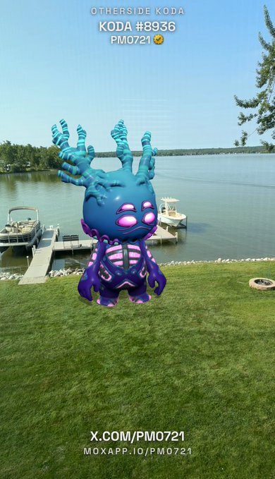 A 3D rendered creature labeled 'OTHERSIDE KODA KODA #8936 PM0721' standing on a grassy lawn near a lake and docks. The purple and teal creature features glowing pink eyes and rib-like patterns, with social media handles 'X.COM/PM0721' and 'MOXAPP.IO/PM0721' displayed at the bottom.