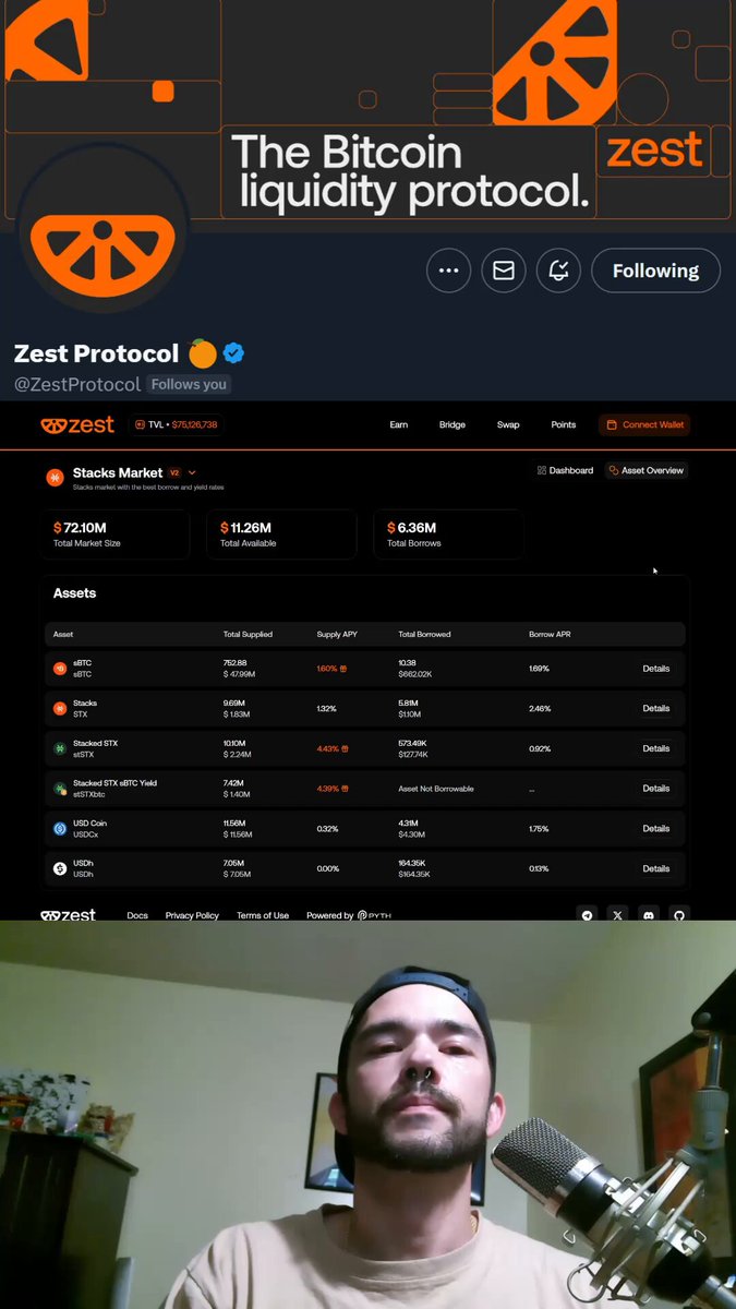 The image features a man wearing a brown shirt, standing behind a microphone with a computer screen displaying a website called "ZestProtocol" that has a logo of an orange fruit. The text on the screen reads "Scrolling, doing my morning routine and stumbled upon something!! Heres the scoop: You can now swap $STX for $ZEST directly on @ZestProtocol !!! More ways to gain access to the most viral token of the cycle right from the mothership!! I am gong to be putting together a video". The man is holding a microphone, and there are two microphones in the image.
