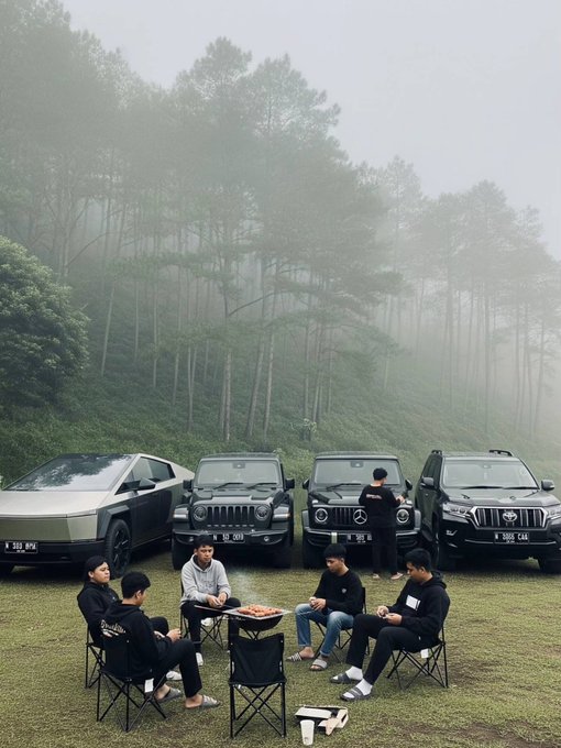 A group of people sit around a small grill on a foggy hillside campsite, backed by four large SUVs including what appears to be a Cybertruck, G-Wagon, and Land Cruiser.