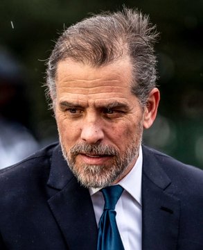 A portrait of Hunter Biden wearing a dark suit and blue tie with a serious expression.