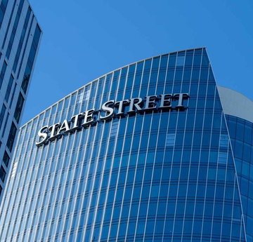 A low-angle architectural shot of a modern glass building with 'STATE STREET' displayed prominently in silver lettering on the blue glass facade.