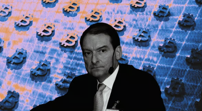 A black-and-white photo of SEC Chairman Paul Atkins appears against a blue background patterned with Bitcoin symbols and stock chart lines, visually linking the regulator's delayed crypto meeting to the digital assets he is preparing to oversee.