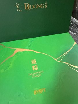 The image features a green box with gold lettering, which appears to be a product packaging for a tea brand. The text "Bybit" can also be seen in the image. The box has been partially opened, revealing its contents inside.