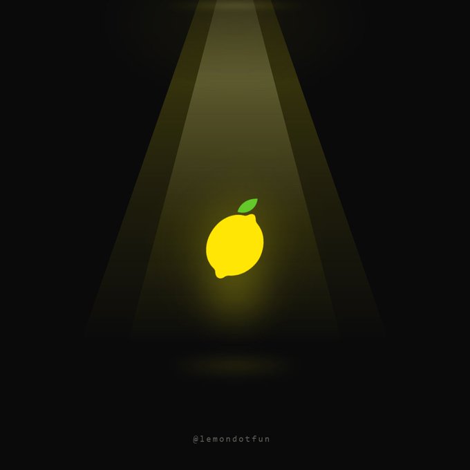 A glowing yellow lemon with a green leaf is illuminated by a spotlight in the darkness, with the text '@lemondotfun' at the bottom.