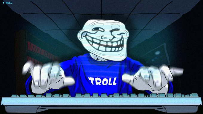 A cartoon Trollface meme wearing a blue shirt labeled "TROLL" sits at a computer keyboard with hands positioned to type in a dark room, with "#TROLL" visible in the top-left corner.