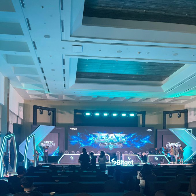 An indoor stage setup for a "MEX Finance" event labeled "BAT 2025," sponsored by Bitget, with attendees gathered in front of the brightly lit platform.