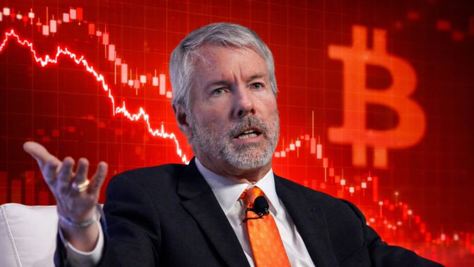 The image features an interview with Michael Saylor about Bitcoin, where he's seen talking about his massive investments into the cryptocurrency. The focal point of the image is Michael Saylor sitting in a chair, wearing a suit and tie, while holding up his hand, possibly gesturing during his speech or explanation about Bitcoin. Behind him, there's an advertisement showcasing a graph with Bitcoin's value displayed on it, emphasizing the importance of Bitcoin in the financial world at that time. The text on the image states "Michael Saylor has spent $63.87 billion buying Bitcoin. Right now, those Bitcoins are worth about $61 billion, so he'S sitting on a paper loss. But instead of worrying or selling, he'S raising more money and buying even more Bitcoin." This message seems to convey Michael's confidence in his decision to invest heavily into Bitcoin despite the losses he has already faced.