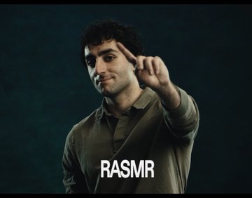 A man in a green shirt points his finger forward at the camera with the text "RASMR" displayed at the bottom of the frame.
