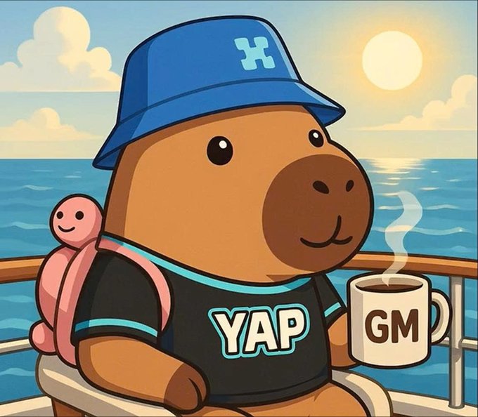 A cartoon illustration of a cheerful capybara wearing a blue hat and a 'YAP' t-shirt with a small pink turtle on its back, holding a 'GM' coffee mug while sitting by the sea at sunset.