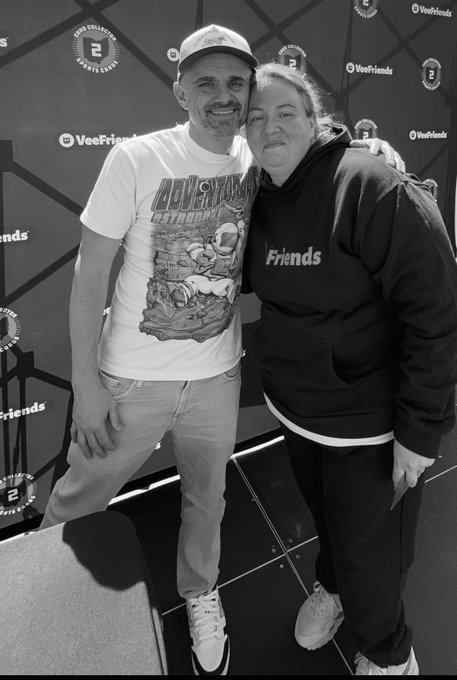 A black-and-white photo shows two people smiling at a VeeFriends event, with the man wearing a Houston Astros t-shirt and the woman wearing a 'Friends' hoodie.
