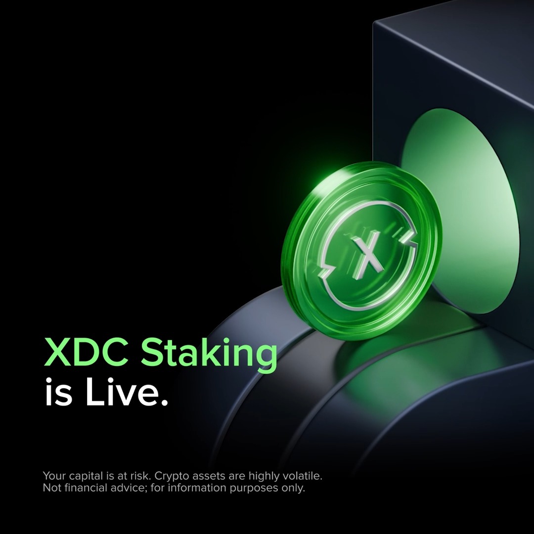 A glossy green XDC token emerges from a dark slot, accompanied by the text "XDC Staking is Live." and a disclaimer about investment risk. The image visually promotes the announcement that Uphold has become the first U.S. digital asset trading venue to offer on-chain XDC staking in partnership with XDCNetwork and Kiln_finance.