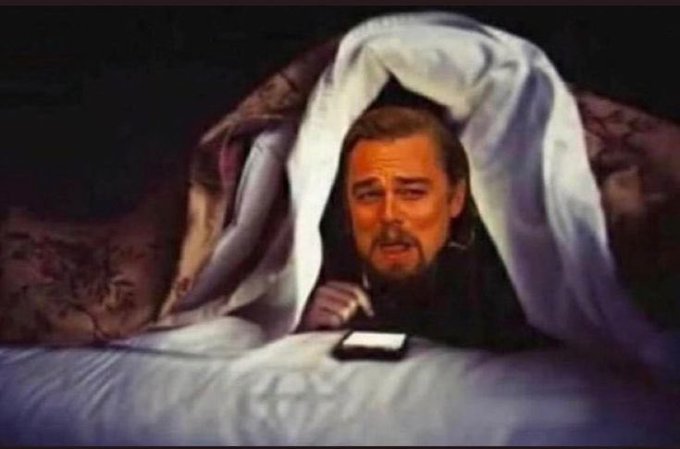The painting shows Leonardo DiCaprio's face digitally edited onto a figure peeking out from beneath a blanket, anxiously looking at a glowing phone in the dark. The caption "All of us checking the Bitcoin price rn" relates to the image by humorously capturing the universal moment of nervously checking a phone for crypto price updates, much like the wide-eyed, anxious expression of the blanket-wrapped figure.