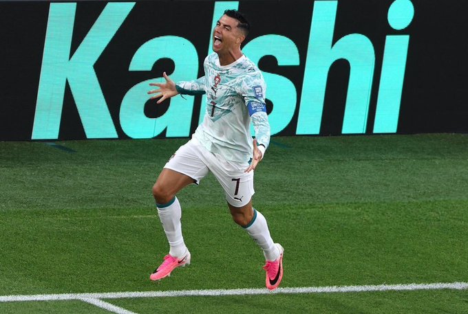 Cristiano Ronaldo, wearing Portugal's number 7 jersey and pink boots, celebrates enthusiastically on the field with his arms outstretched during a match.