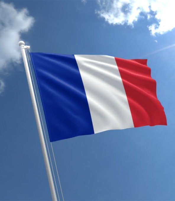 The French flag waves against a blue sky, symbolizing the nation behind the newly proposed 31.4% tax on crypto-to-stablecoin swaps that would apply even without cashing out to traditional money.