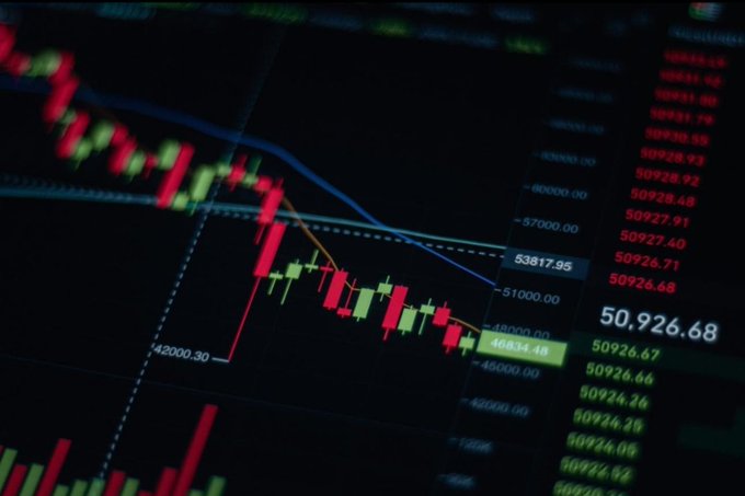 A financial chart displays a sharp downward candlestick trend with prices falling from above 53817.95 toward 46844.48, accompanied by red numerical data columns showing values like 50926.68, 50926.67, and 50926.66 in the right-hand readout. The steep decline visually reinforces the post's message of Bitcoin trading under pressure as risk sentiment weakens, illustrating the kind of price drop that historically has presented accumulation opportunities when confidence fades.