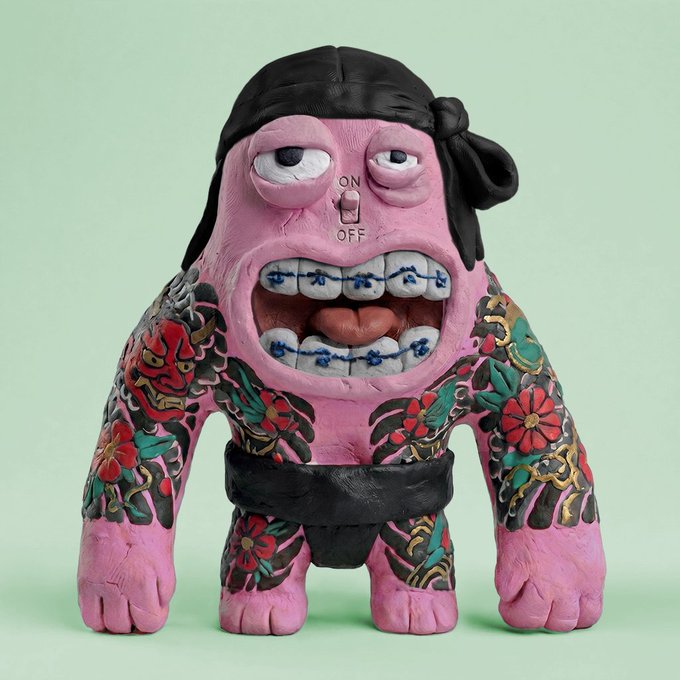 A pink, tattoo-covered figurine with braces, a black bandana, and an "ON/OFF" switch on its face grins against a mint green background, embodying the weird, collectible charm of "internet magic jpegs." The quirky, handcrafted toy aesthetic reflects the playful, meme-worthy spirit of digital art collectibles.