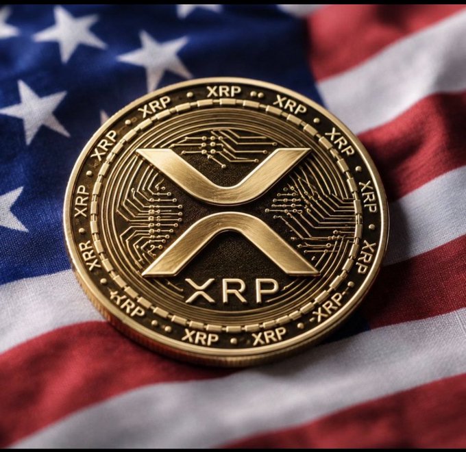 A gold-colored physical coin representing the XRP cryptocurrency rests on the fabric of an American flag.
