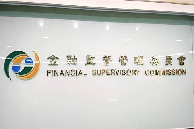 A sign on a glass wall for Taiwan's Financial Supervisory Commission (金融監督管理委員會), featuring its green and blue circular logo.