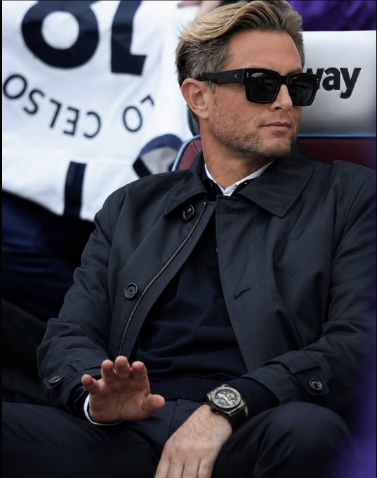 A blonde man wearing dark sunglasses, a navy coat, and a watch sits with a 'CELSO' banner partially visible in the background.