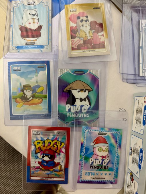 A collection of 'Pudgy Penguins' trading cards in protective sleeves, showing various character designs and priced at 740 and 50.
