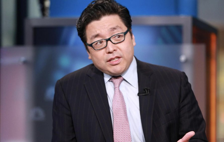 A man in a dark pinstripe suit, light blue shirt, and patterned tie, wearing black-rimmed glasses, speaks in what appears to be a television studio setting, likely delivering commentary related to the bullish XRP prediction attributed to Tom Lee in the post.