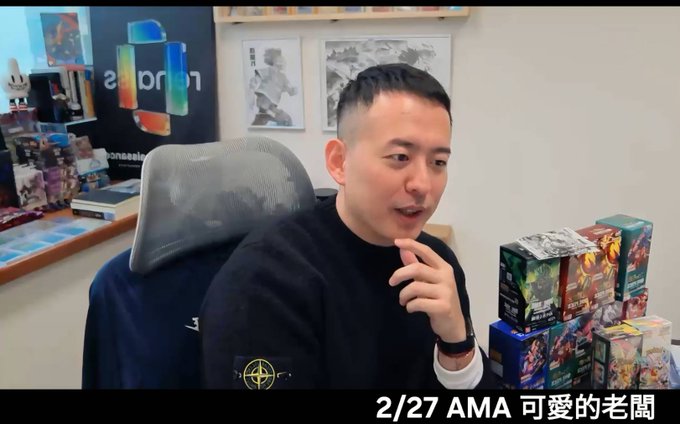 An Asian man sits in a chair in a room with collectibles, with text reading '2/27 AMA 可愛的老闆' and the logo 'abon' visible in the background.